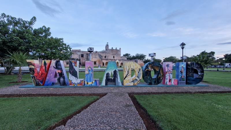 Valladolid letters in het park Het Valladolid bord in het park met een breed wandelpad en groen ervoor.