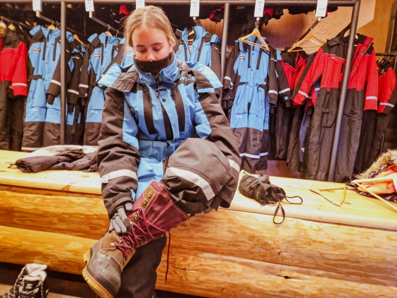 We trekken stevige winterlaarzen aan in de kleedruimte vóór de tour sneeuwscooter in Tahko