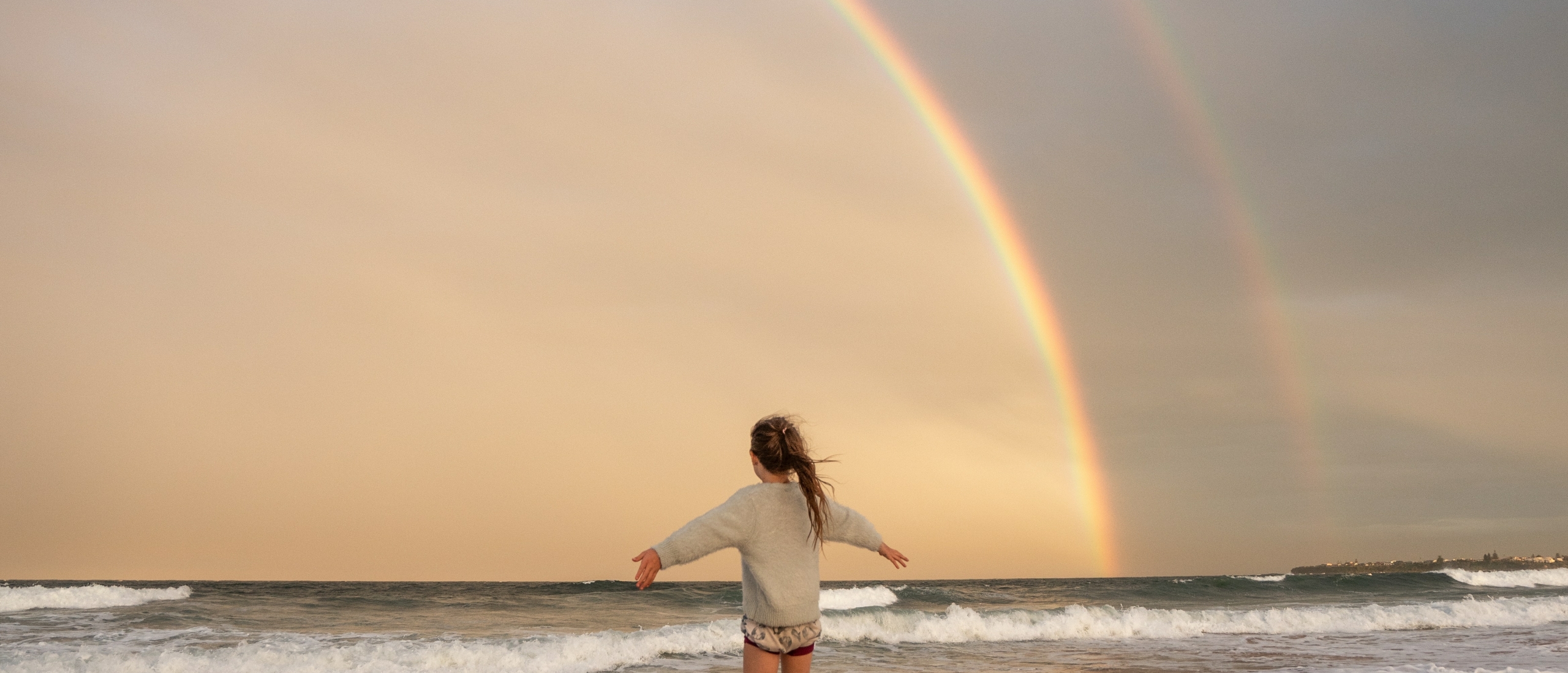 Kind op strand in regenboog aura