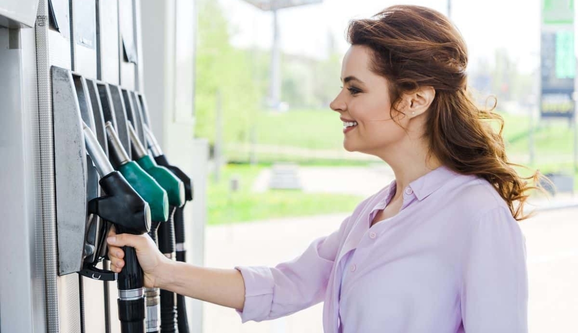 Vrouw pakt een vulpistool bij tankstation