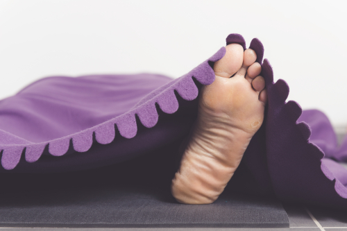 Voet op een yogamatje met dekentje eroverheen