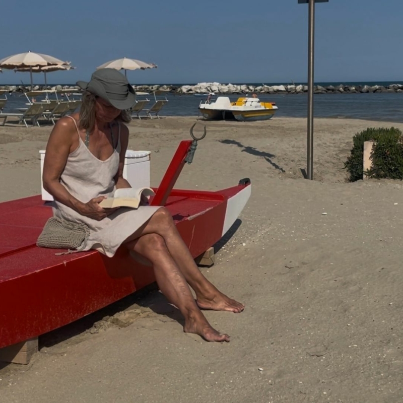 Linda Thuijs op strand leest boek Een vlecht van heilig gras
