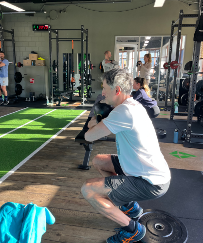 Groep sporters doet push-ups op het strand tijdens een intensieve bootcamp in Scheveningen.
