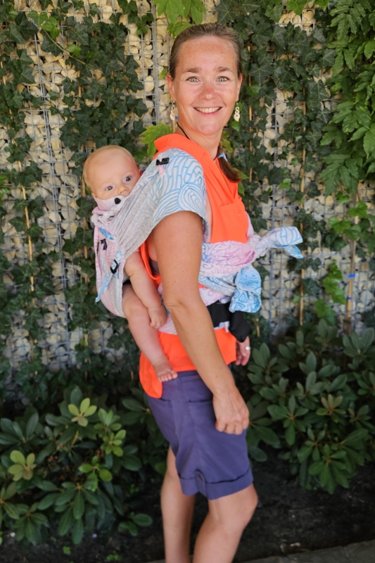 Baby van zes maanden op de rug gedragen in een ergonomische draagzak