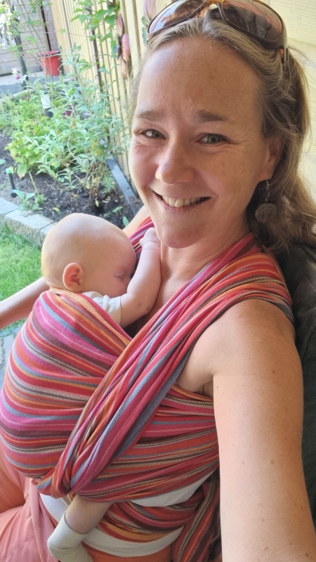 Moeder draagt haar pasgeboren baby zittend om haar bekken te ontzien