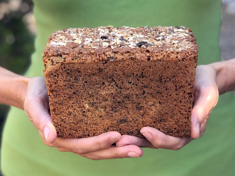 Glutenvrij zaden- en pittenbrood in handen Marije met groen T-shirt