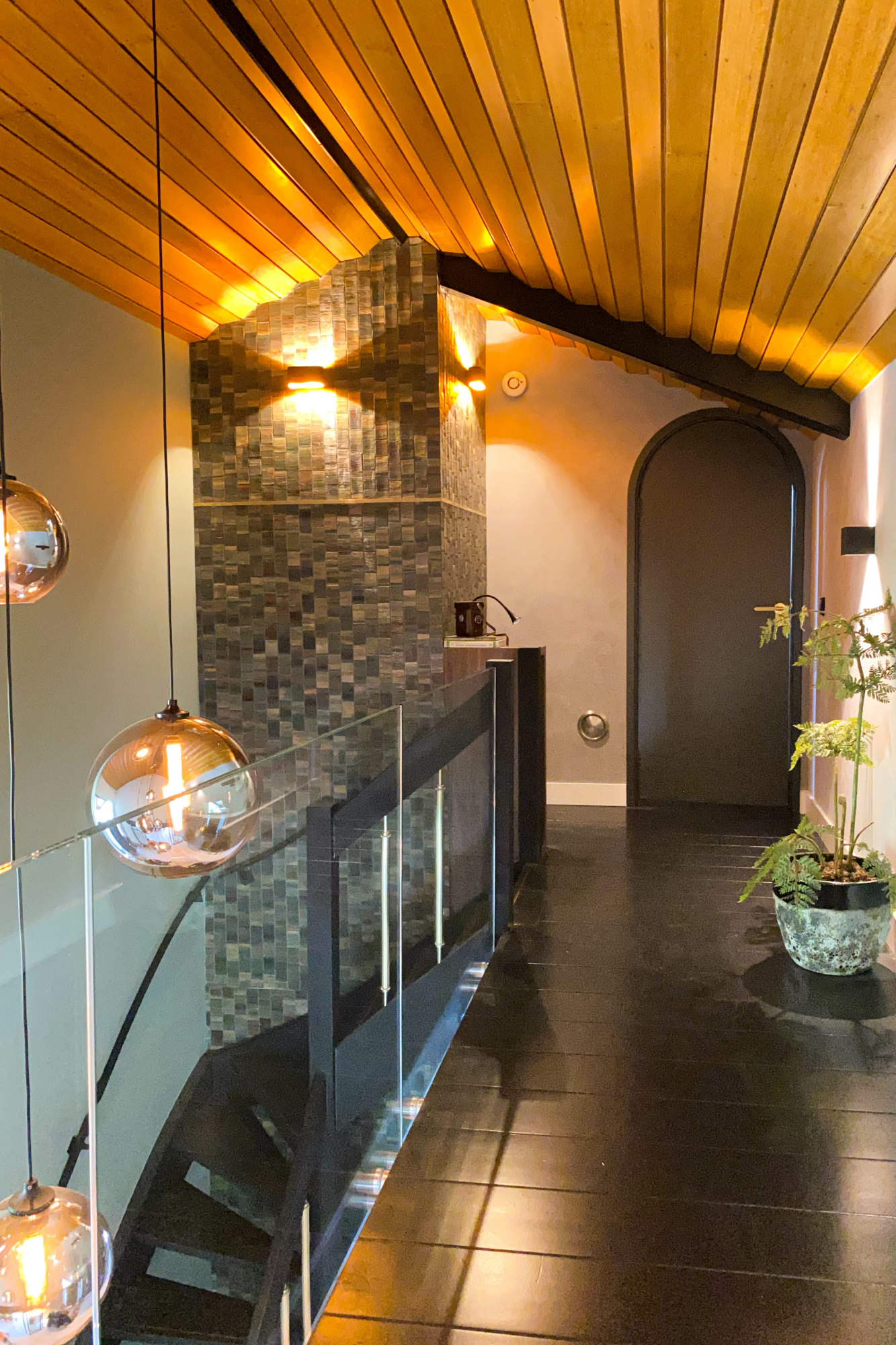De vide in de hal met het markante '70's plafond, het zachtgroene behang, de nieuwe glazen balustrade