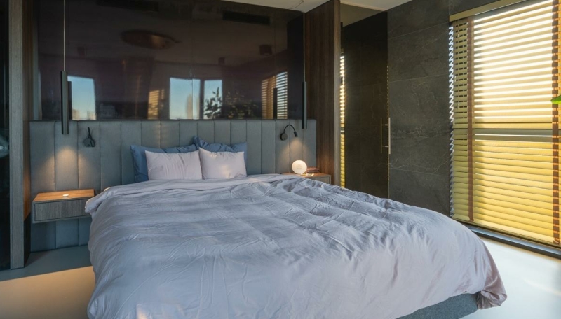 Hoofdslaapkamer in penthouse met uitzicht en zonfilterende lamellen, reflectie van de skyline in het bedhoofd