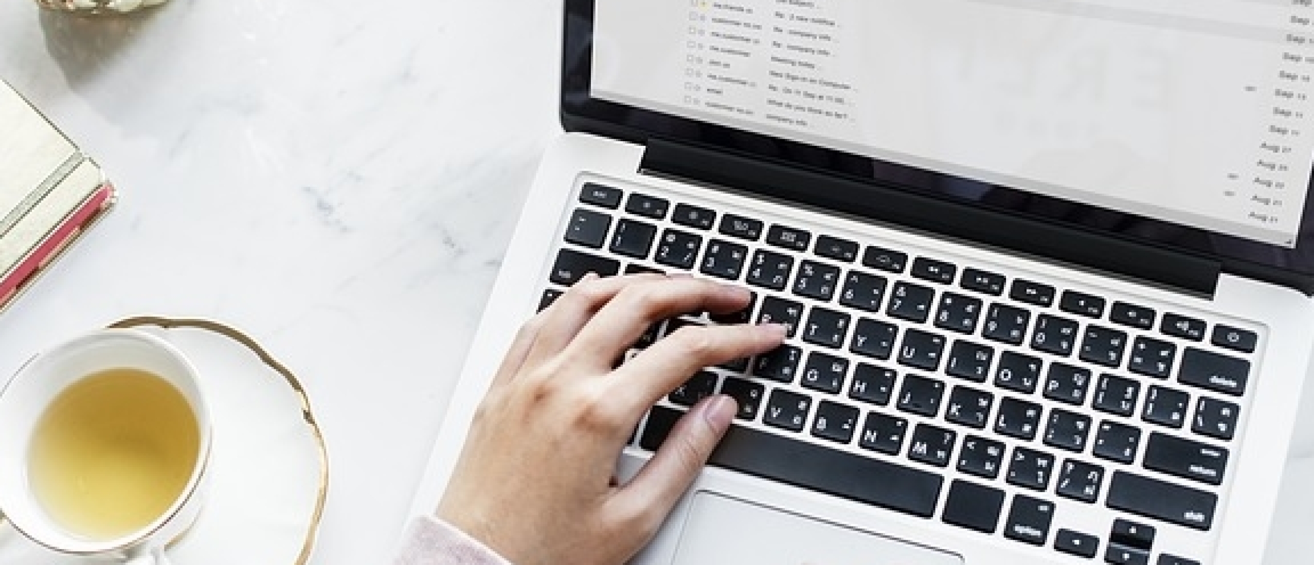 vrouw op laptop met kop thee