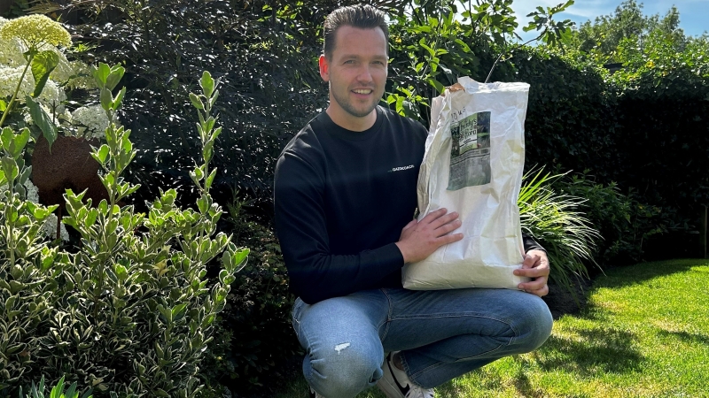 Zak wormencompost voor gazon en tuin Persoon met een zak wormencompost voor gazon en tuin