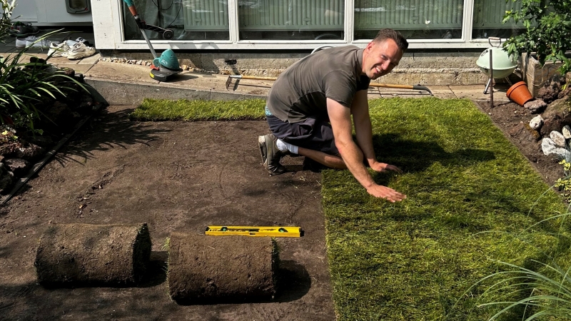 Graszoden leggen op een voorbereide bodem in de tuin