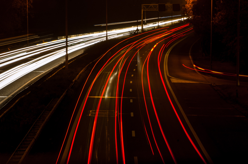 Auto lichtspoor fotografie op snelweg in het donker met lange sluitertijd en rood-witte lichtstrepen.