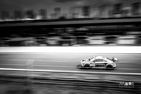 Panning-foto van een racende Audi Sport-wagen op een circuit, met bewegingsonscherpte in de achtergrond