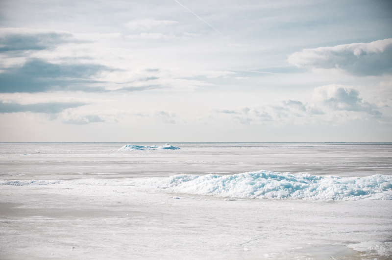 Besneeuwd strand met lage wolkenlucht en schuimende golven, als voorbeeld van sneeuw fotograferen aan de kust