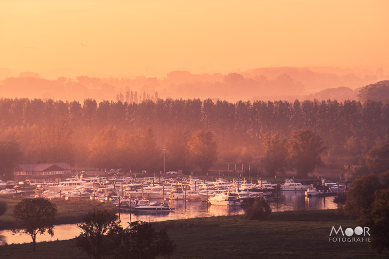 Jachthaven bij zonsopkomst met zachte mist en gouden licht – landschapsfotografie in de herfst.