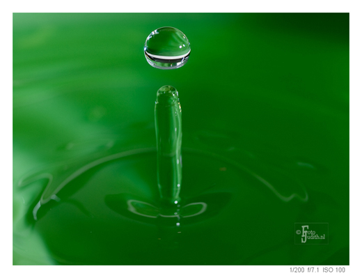 Zwevende waterdruppel boven een wateroppervlak, als voorbeeld van creatieve druppelfotografie met scherpstelling en timing