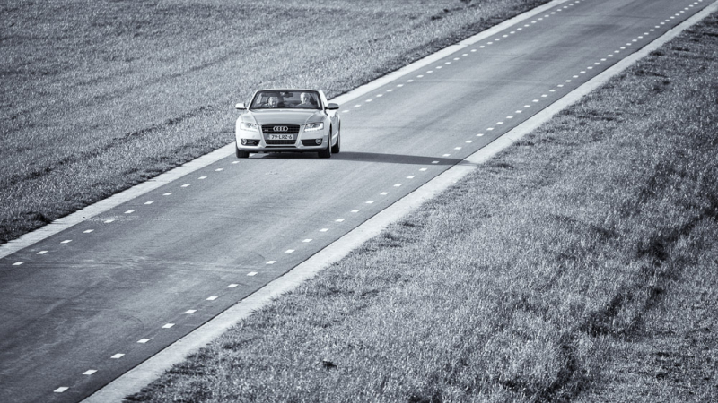 Zwart-witfoto van een auto op een lange weg die laat zien hoe perspectief verandert door het standpunt