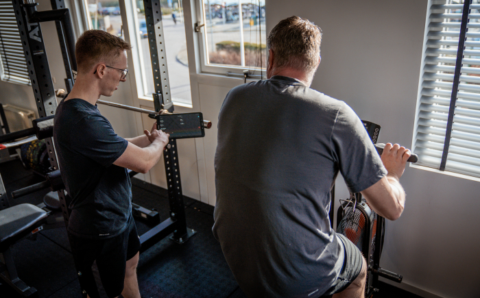 Personal trainer legt iets uit aan sporter