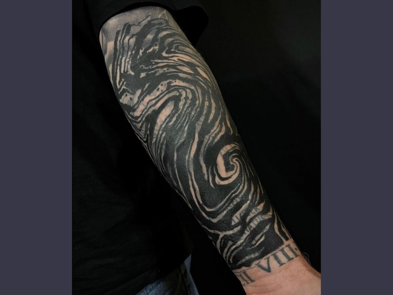Blackwork tattoo golven op onderarm