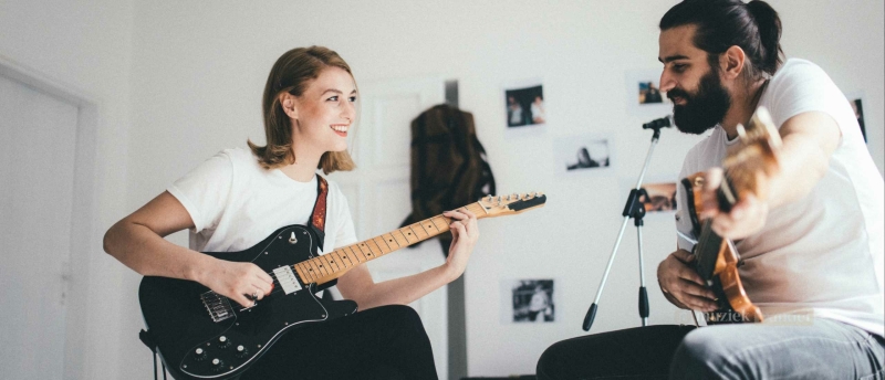 Muzikanten die samen spelen op verschillende instrumenten zoals gitaar, piano en drums.