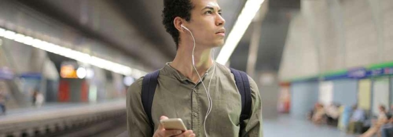 Man met bedrade oordopjes in metrostation