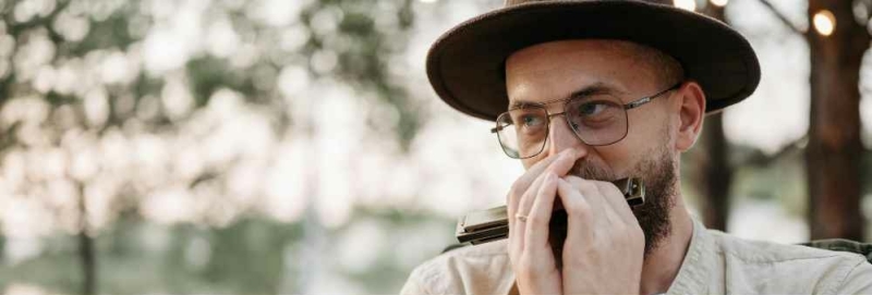 Man speelt mondharmonica in bos