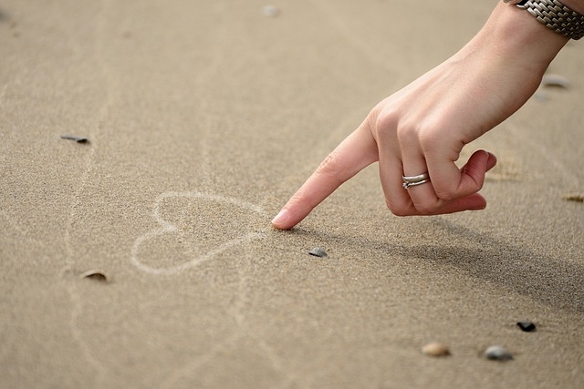 hand die in het strand zand een hartje tekent