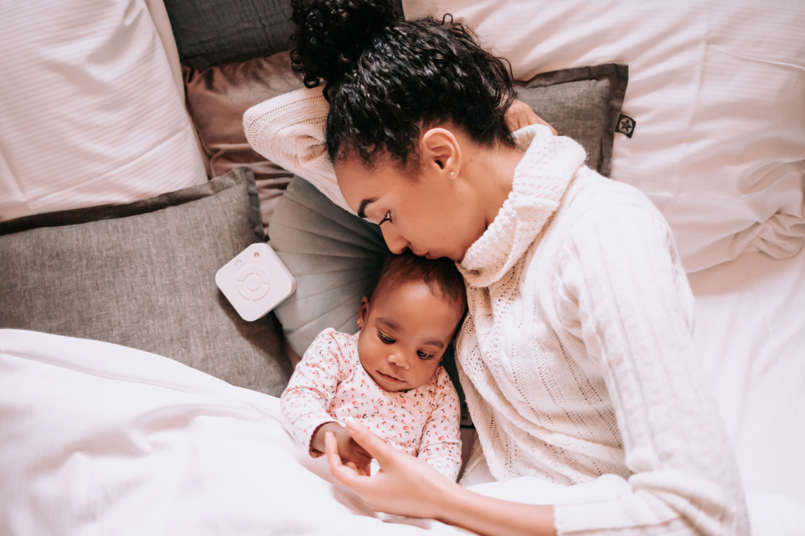 Vrouw met kindje in bed, daarnaast ligt een Numsy White Noise machine