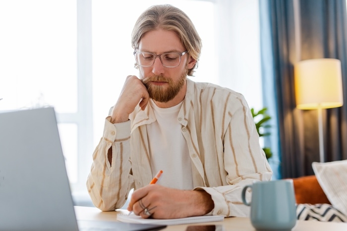 Man schrijft aan zijn bureau met pen en papier