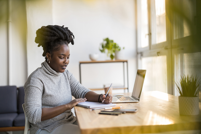 Vrouw schrijft aan een bureau aan het raam