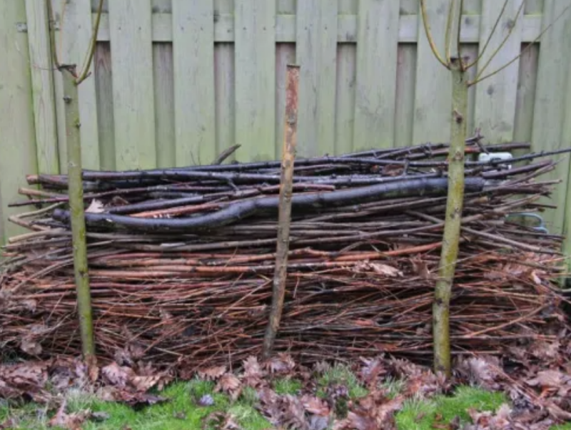 Takkenril van snoeiafval als natuurlijke tuinafscheiding