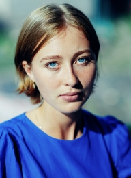 vrouw in blauwe blouse kijkt in camera