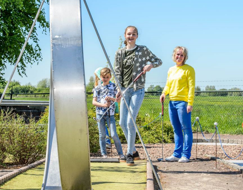 Blij midgetgolfspelers, moeder met kinderen, op de crazygolfbaan met de megalooping