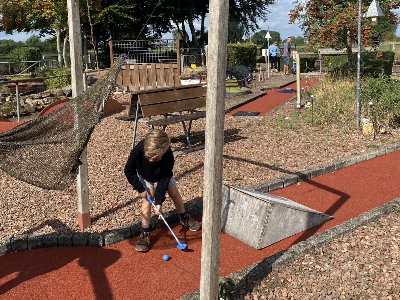 Jongetje op de minigolfbaan bij de schans met net