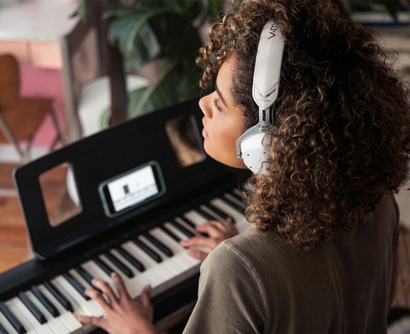 Roland FP-10 digital piano gespeeld door een jonge vrouw met hoofdtelefoon op Roland FP-10 digitale piano met 88 gewogen toetsen