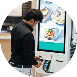 Iemand die een betaling op een bestelzuil pinautomaat doet met hun telefoon