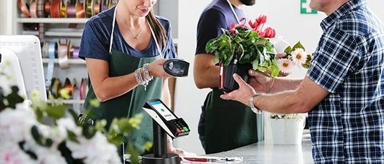 Iemand die bloemen afrekent met een CCV Nexus Pad A35 die je kan kopen bij PinDirect
