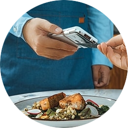 Twee mensen in een restaurant die een contactloze betaling op een kassagekoppelde CCV Compact A77C pinautomaat uitvoeren