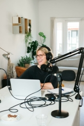 Dame achter microfoon en laptop die podcast opneemt