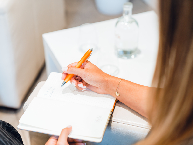 Een vrouw schrijft persoonlijke, praktische tips tijdens een coaching sessie