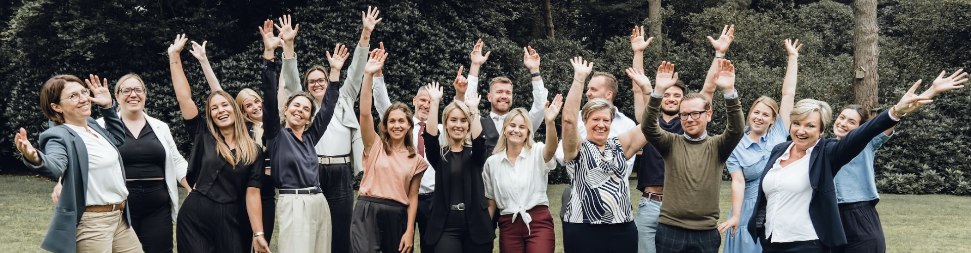 groep mensen heeft een teamtraining gedaan bij Qlick en straalt zelfvertrouwen uit in de tuin van Qlick in Kapellen