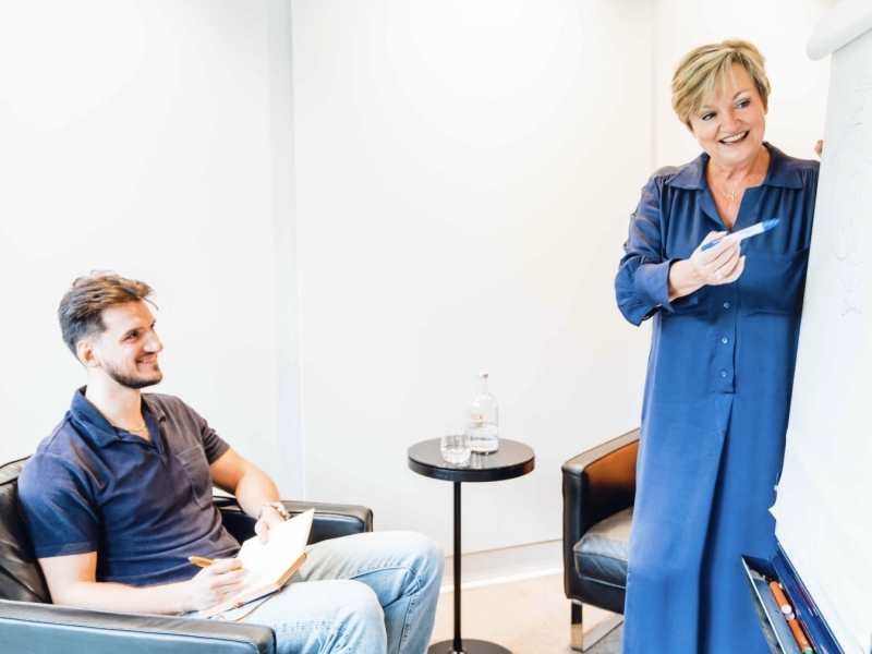 vrouw geeft persoonlijke coaching over leiderschap en schrijft praktische tips op een bord