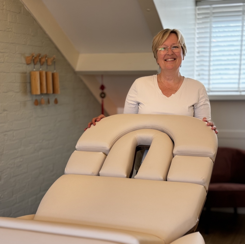 Margôt trots bij haar massagetafel en praktijk