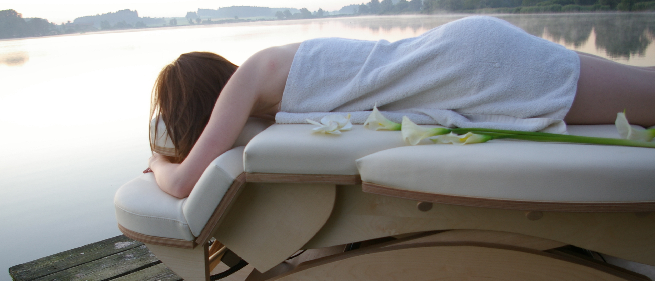 Vrouw op massagetafel bij steiger aan meer
