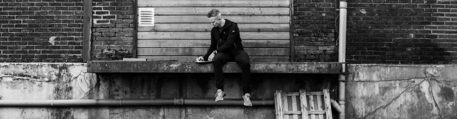 Een personal trainer die op een muurtje zit en iets opschrijft.