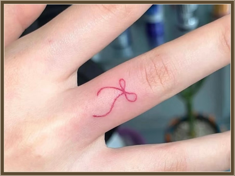 ribbon on finger tattoo