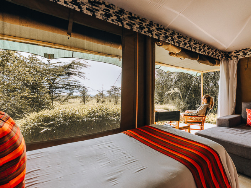 Canvas safaritenten met savannezicht bij Zebra Plains Mara Camp in Kenia Reiziger zittend op het privéterras van een middenklasse canvas tent bij Zebra Plains Mara Camp in de Masai Mara Kenia