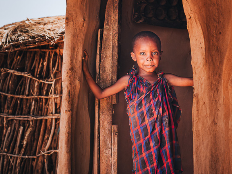 Bezoek aan een Maasai-dorp in Tanzania Maasai jongetje tijdens een respectvol bezoek aan een Maasai-dorp als onderdeel van een safari in Tanzania