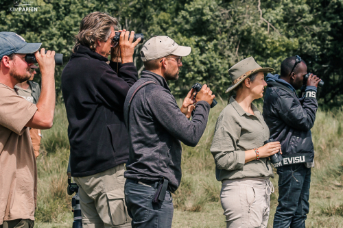 Vogels Spotten met Verrekijker tijdens wandelsafari in Masai Mara Groep reizigers gebruikt verrekijkers om vogels te spotten tijdens een wandel safari door de Afrikaanse savanne