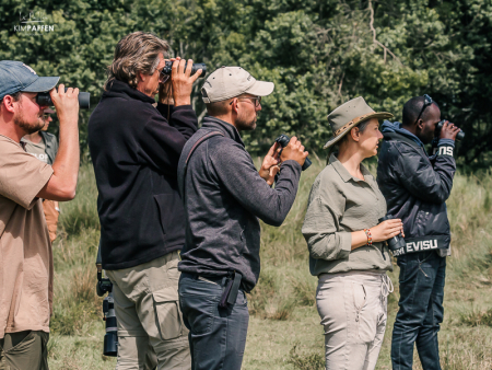 Groep reizigers gebruikt verrekijkers om vogels te spotten tijdens een wandel safari door de Afrikaanse savanne